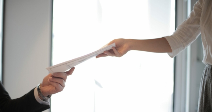 Canva-Job-Applicant-Passing-Her-Documents-scaled-1920x1020-c-default